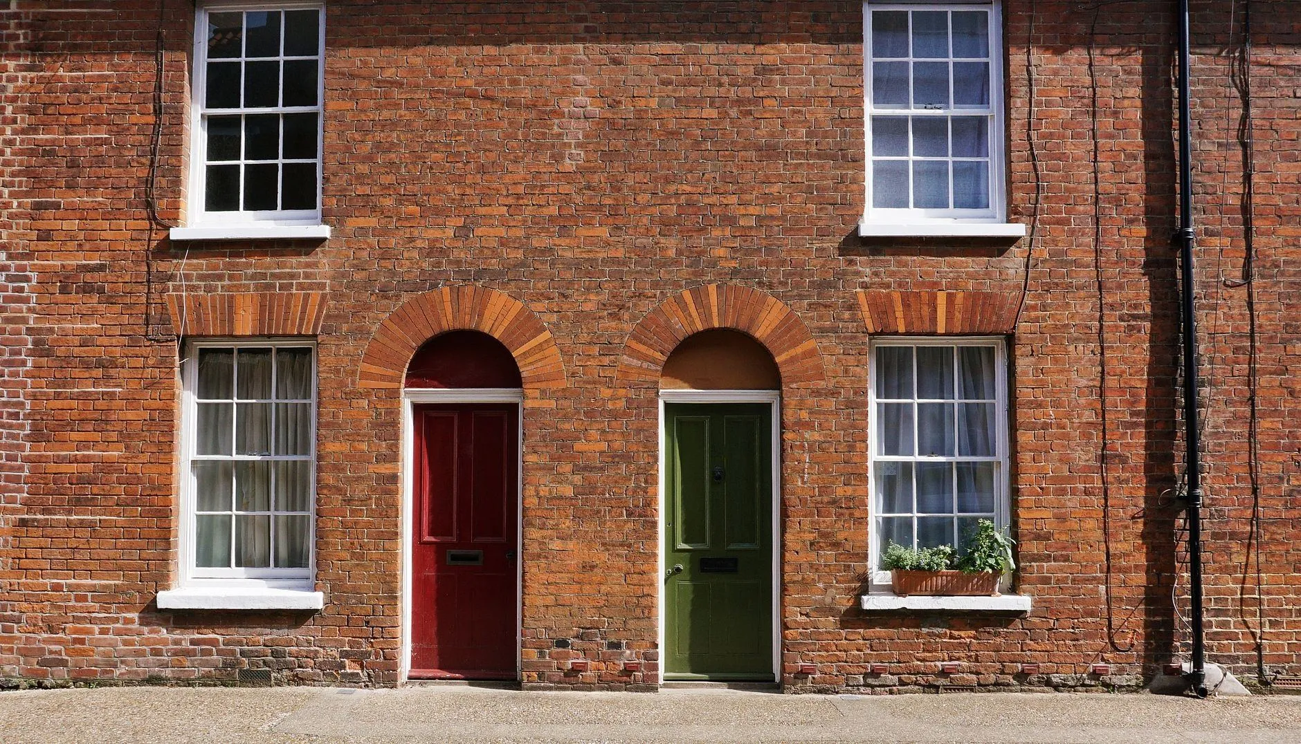 Red-brick terraced houses with arched doorways and white sash windows on a quiet pavement